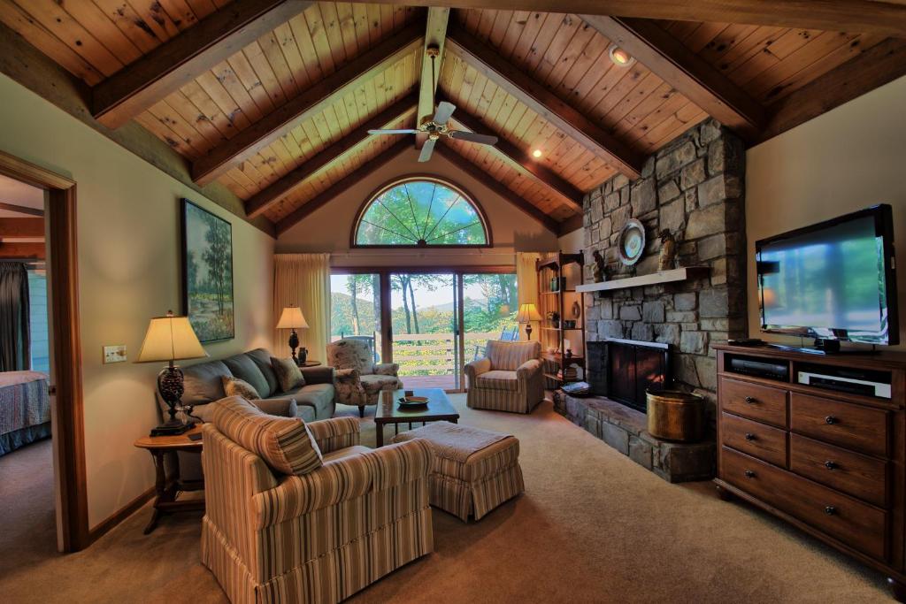 a living room with a stone fireplace and a tv at Penrith Hideaway at Yonahlossee in Boone