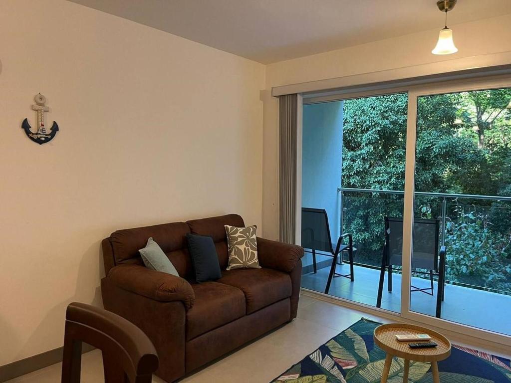 a living room with a couch and a large window at Stunning 2 Bedroom Apartment in Punta Esmeralda , Costa Rica in Punta Leona