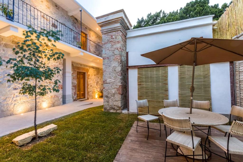 Hotel Tabáa Oaxaca في مدينة أواكساكا: فناء مع طاولة وكراسي ومظلة