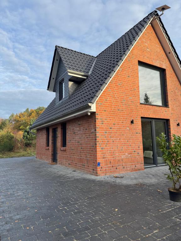 a red brick house with a black roof at Lütte Lina in Neuenkirchen