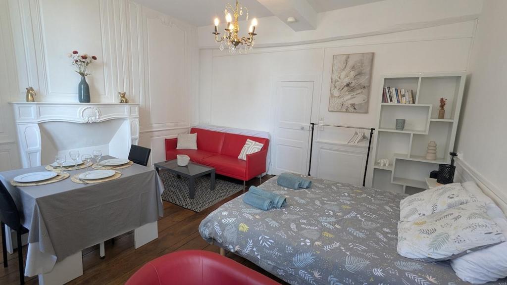 a living room with a bed and a red chair at Appartement Hyper Centre, 1er étage in Fougères