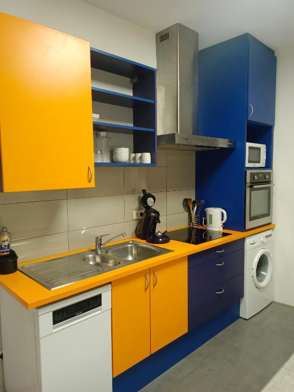 een keuken met gele en blauwe kasten en een wastafel bij Le nid in Colmar