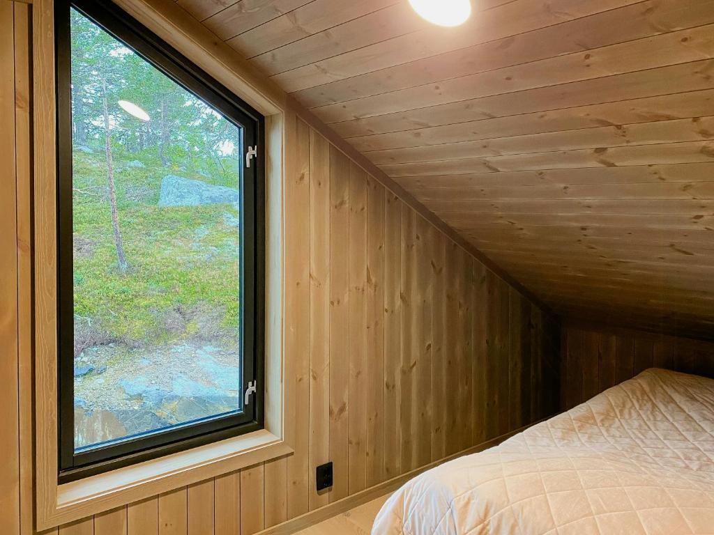 ein Schlafzimmer mit einem Fenster in einer Holzwand in der Unterkunft Modern Family Cabin By The Ski Trail In Tuddal in Tuddal