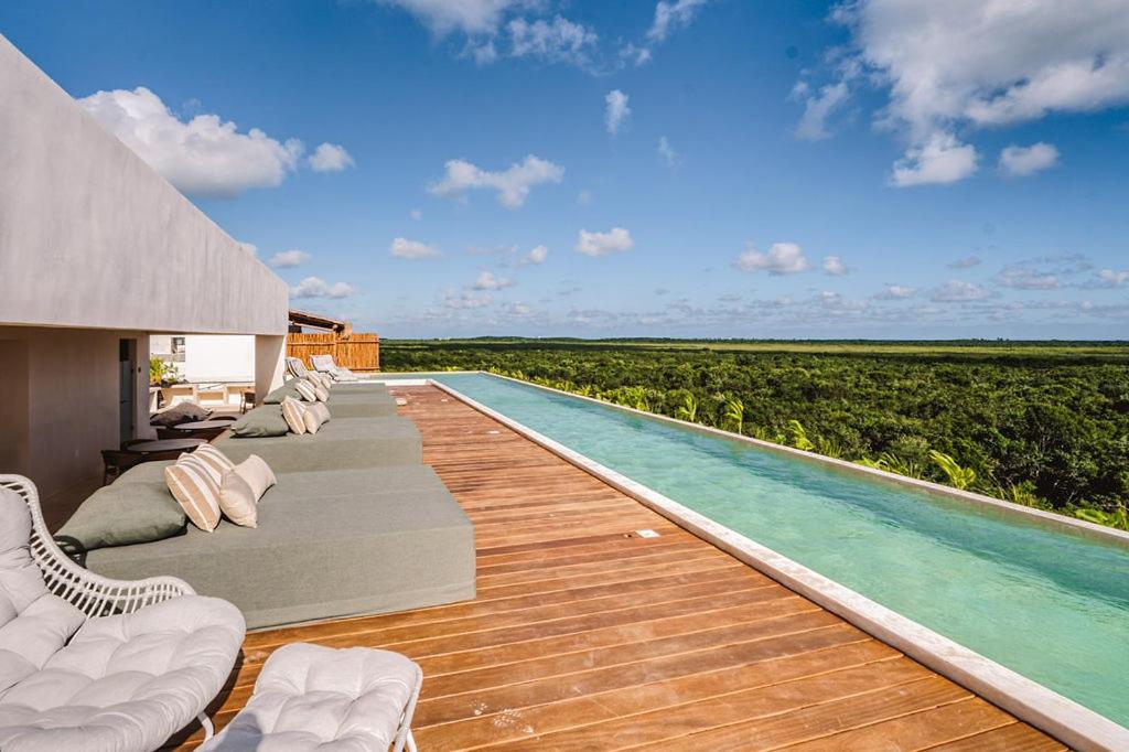 a pool with chaise lounge chairs and a wooden deck at Divine 2BR with Beach Access Gym Fast WiFi in Cedro