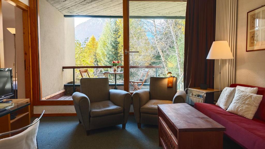 Una sala de estar con un sofá y sillas y una ventana grande. en Hostdomus - Design Suite R10, en San Sicario