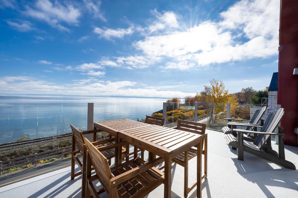 a table and chairs on a balcony with a view of the water at Panorama 1253: Two-Level Sanctuary & Views in Petite-Rivière-Saint-François