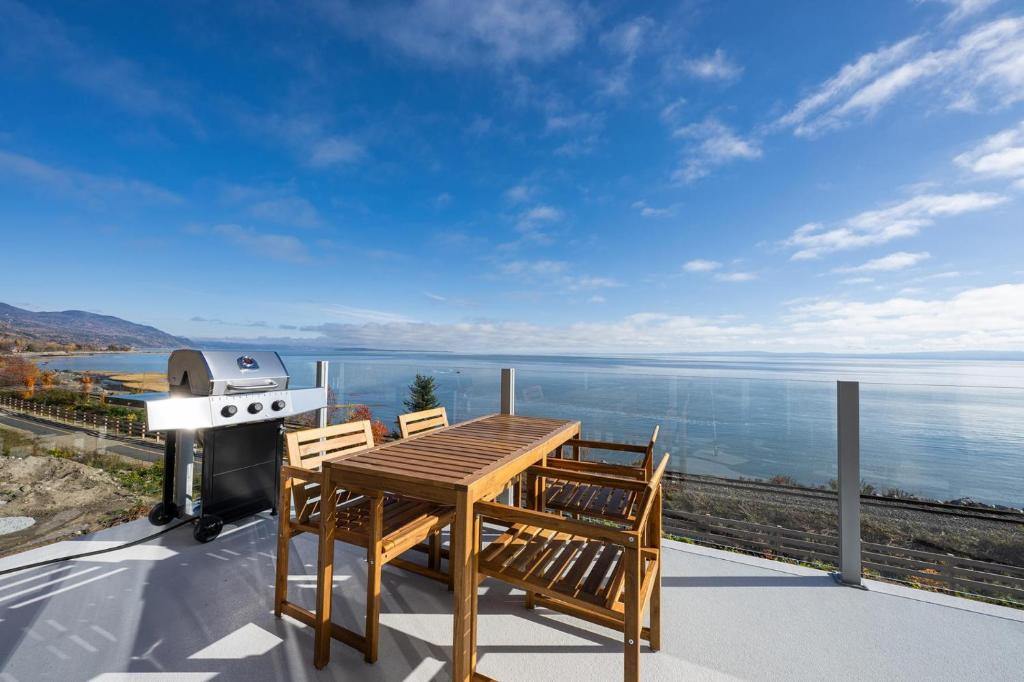 a table and chairs on a balcony with a grill at Panorama 1253: St. Lawrence View, Spacious Terrace in Petite-Rivière-Saint-François