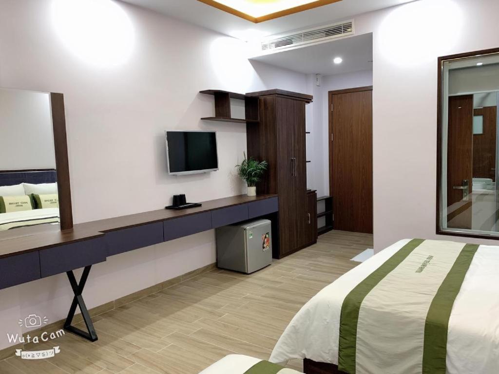 a bedroom with a bed and a tv on a wall at La Maison in Cat Ba