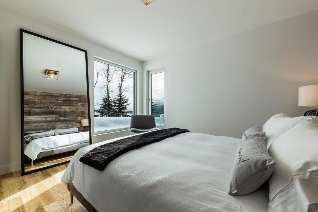 a bedroom with a large white bed and a large window at Le Rupin 77: Luxury Contemporary, Spa, River View in Petite-Rivière-Saint-François