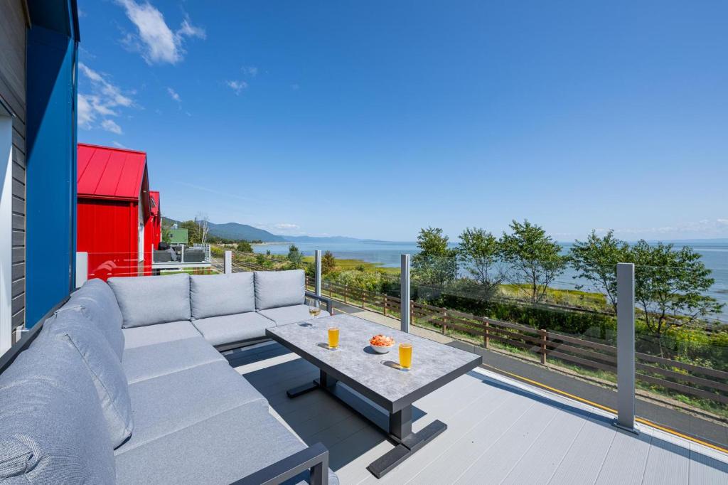 ein Wohnzimmer mit einem Sofa und einem Tisch auf dem Balkon in der Unterkunft Mer et Mont 1223: Spa & River Views Near Le Massif in Petite-Rivière-Saint-François