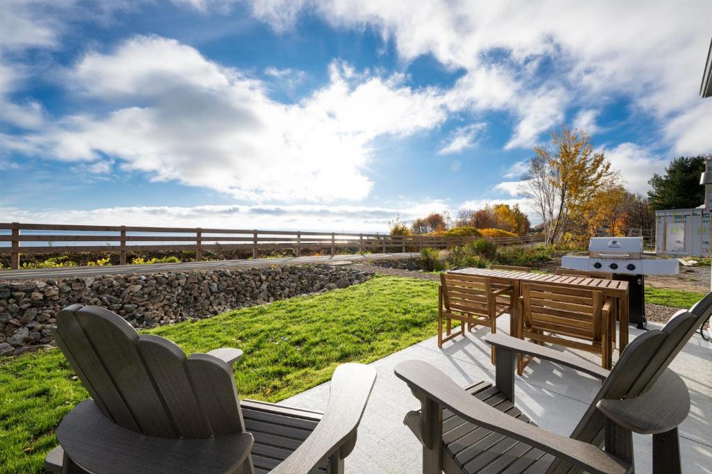 a deck with chairs and a bench on a patio at Panorama 1249, Majestic River View, Spacious Patio in Petite-Rivière-Saint-François