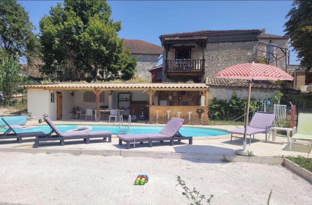 a pool with chairs and an umbrella and a house at La P'tite Maiz in Bourg-de-Visa