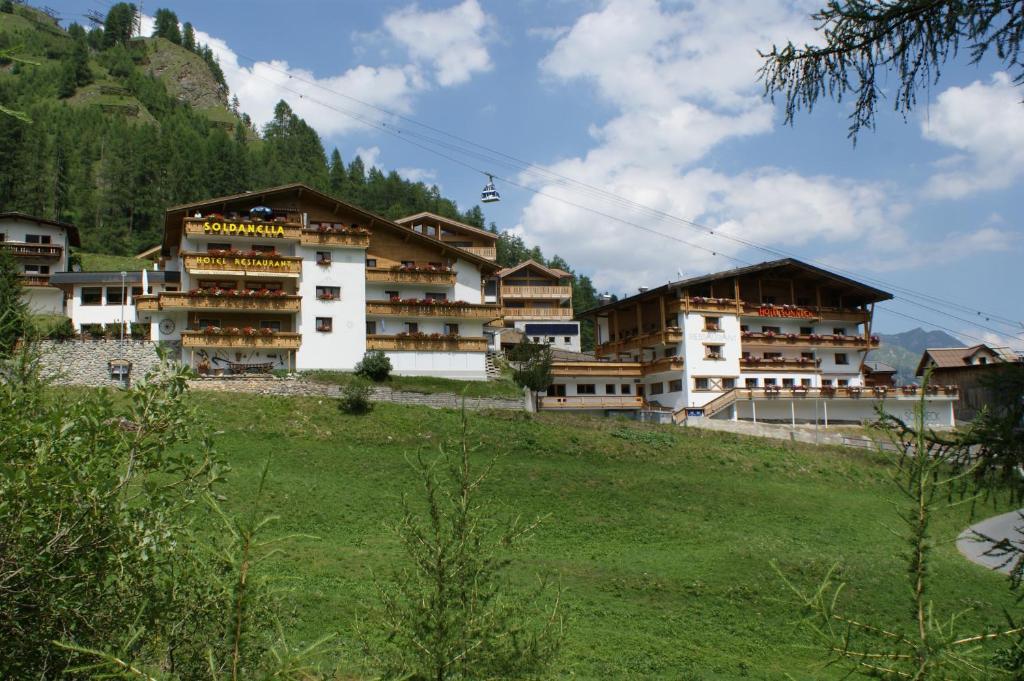 a group of buildings on a hill with a field at Sonnenhotel Soldanella Sonneck in Samnaun