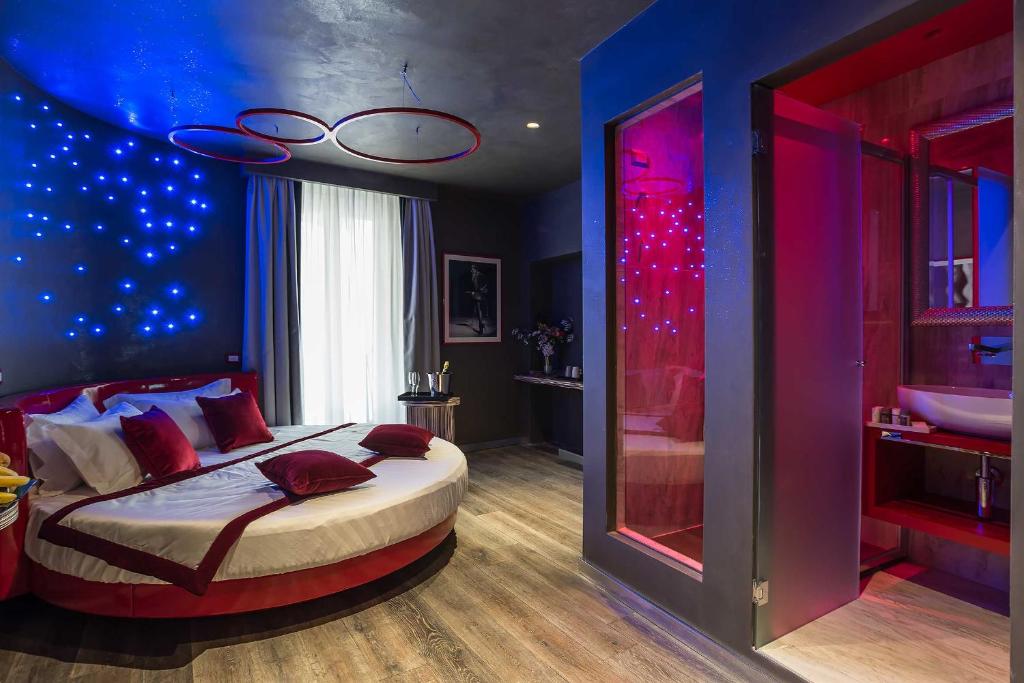 ローマにあるコロンナ スイート デル コルソのベッドルーム1室(青と赤の照明が付いたベッド1台付)