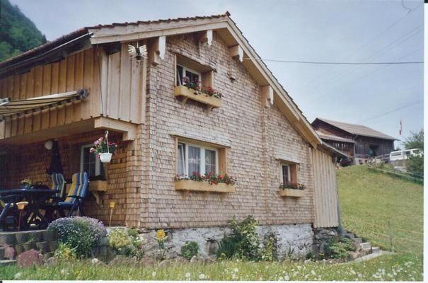 una pequeña casa de ladrillo con 2 ventanas y flores en Fäsch, en Flumserberg