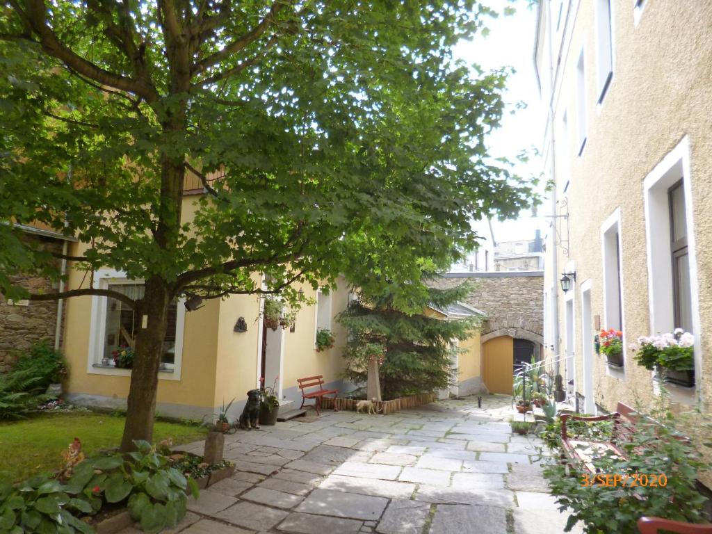 a courtyard of a building with a tree and benches at Ferienwohnung Im Vierseitenhof in Annaberg-Buchholz