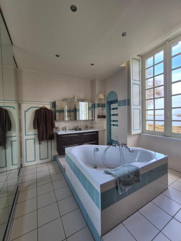 a large bathroom with a large tub and a kitchen at Le Petit Serrant - maison d'hôtes d'exception in Bouchemaine