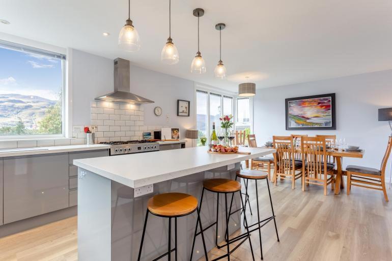 a kitchen with a large island with bar stools at Foinaven House in Ullapool