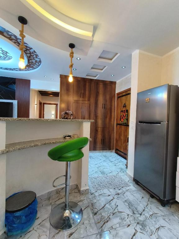 a green stool in a kitchen with a refrigerator at Dar El Ommda in Tozeur
