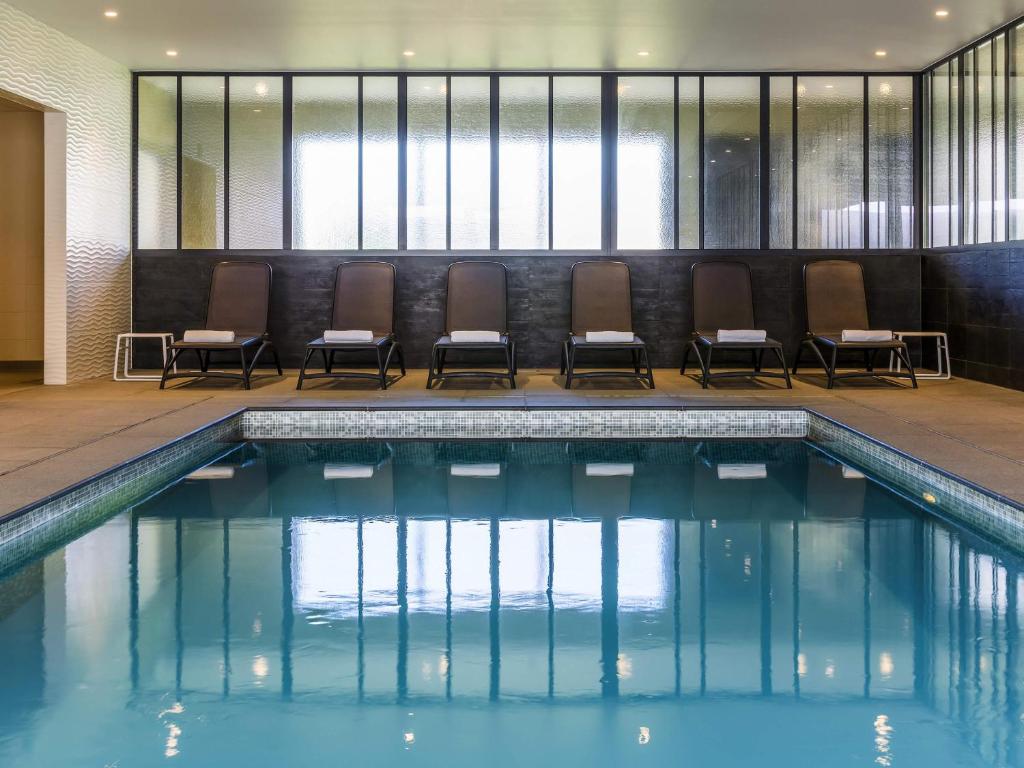 a swimming pool with chairs in a building at ibis Styles Nieuwpoort in Nieuwpoort