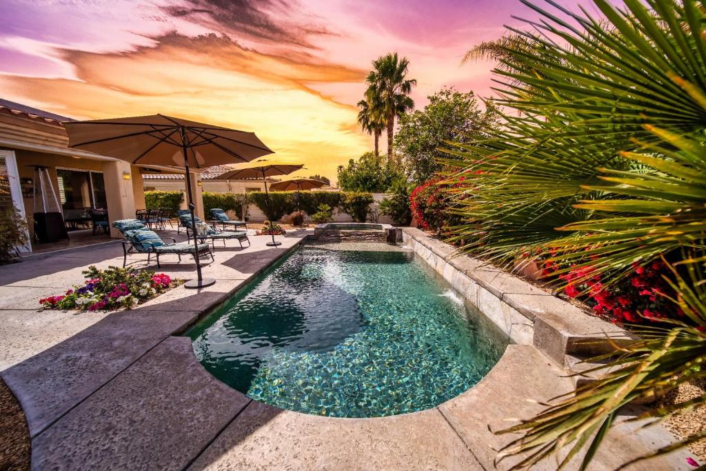a swimming pool with an umbrella in a backyard at Luxurious Custom-built Villa Pool Spa Fire Pit more in Palm Desert