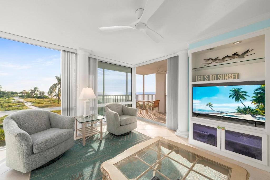 a living room with a large screen tv and two chairs at Island Beach Club #340E in Sanibel
