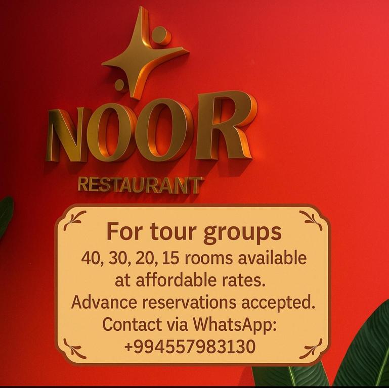 a sign that says noor restaurant on a red wall at Noor-ZamZam-Madinah Halal Hotels Group in Baku
