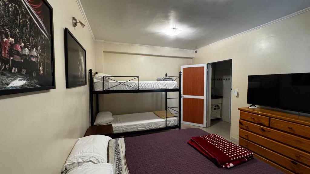 Sumaq Hostel Backpackers في بوينس آيرس: غرفة بسريرين بطابقين وتلفزيون بشاشة مسطحة