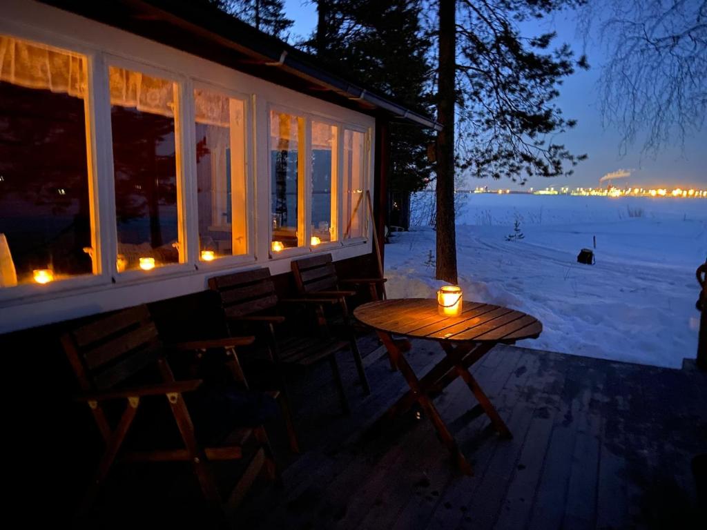 einen Tisch und Stühle auf einer Veranda mit Kerzen in der Unterkunft Metsäpirtti merenrannalla in Oulu