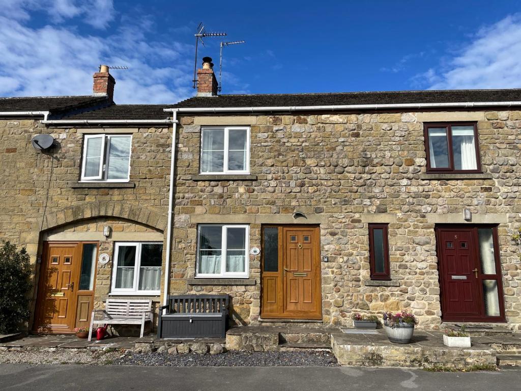 a stone house with a bench in front of it at Tyg Cottage in Grewelthorpe