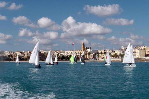 un grupo de veleros en el agua con una ciudad en el fondo en Merzuq House, en Birżebbuġa