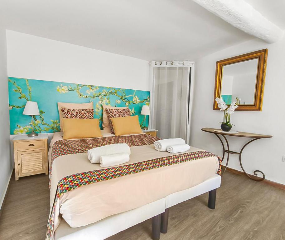 a bedroom with a large bed with yellow and orange pillows at Les Amandiers - L'Isle d'Or in LʼIsle-sur-la-Sorgue