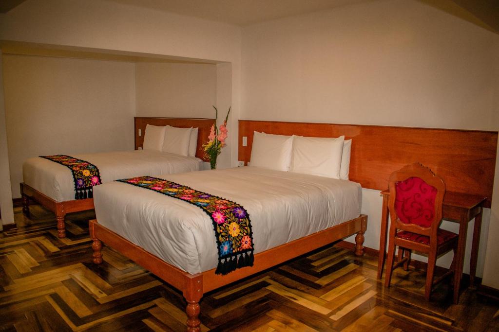 una camera da letto con due letti, un tavolo e una sedia di Kantu hotel a Cuzco
