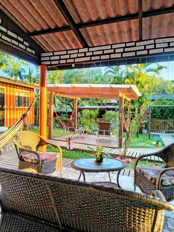 a patio with chairs and a table and a swing at Pousada Recanto das Cores in Ilha do Mel