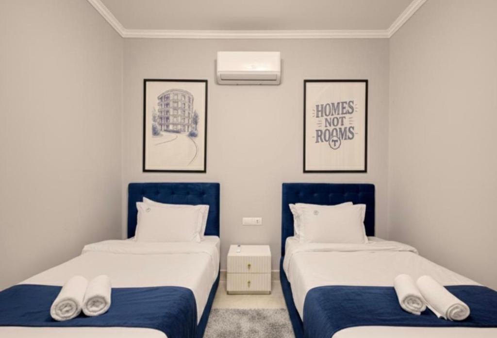 duas camas em um quarto com azul e branco em Lumora Pyramids InN em Cairo