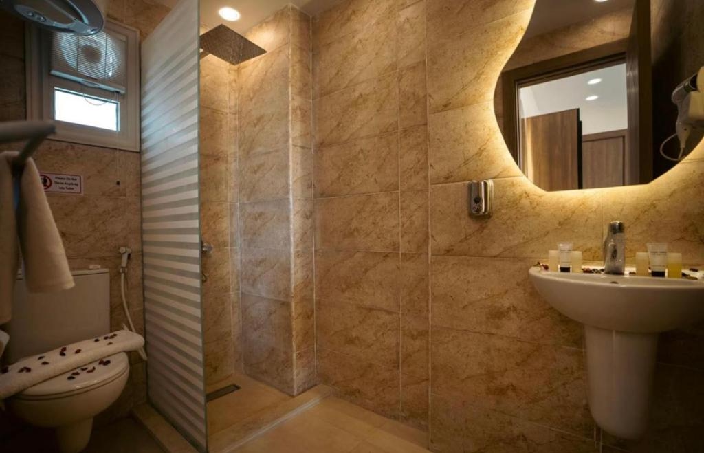 een badkamer met een wastafel, een toilet en een spiegel bij Lumora Pyramids InN in Caïro