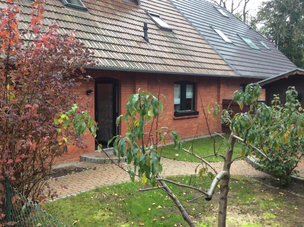 une maison en briques rouges avec un arbre devant dans l'établissement Ferienwohnung In Neustrelitz Mit Garten Und Grill, à Neustrelitz