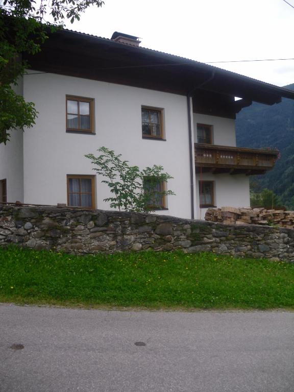 a white house with a stone wall in front at Nagelehof 3 in Ainet