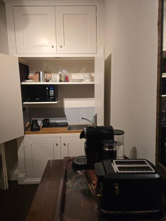 a kitchen with white cabinets and a counter top at Accommodation in Dorset, Sherborne in Sherborne