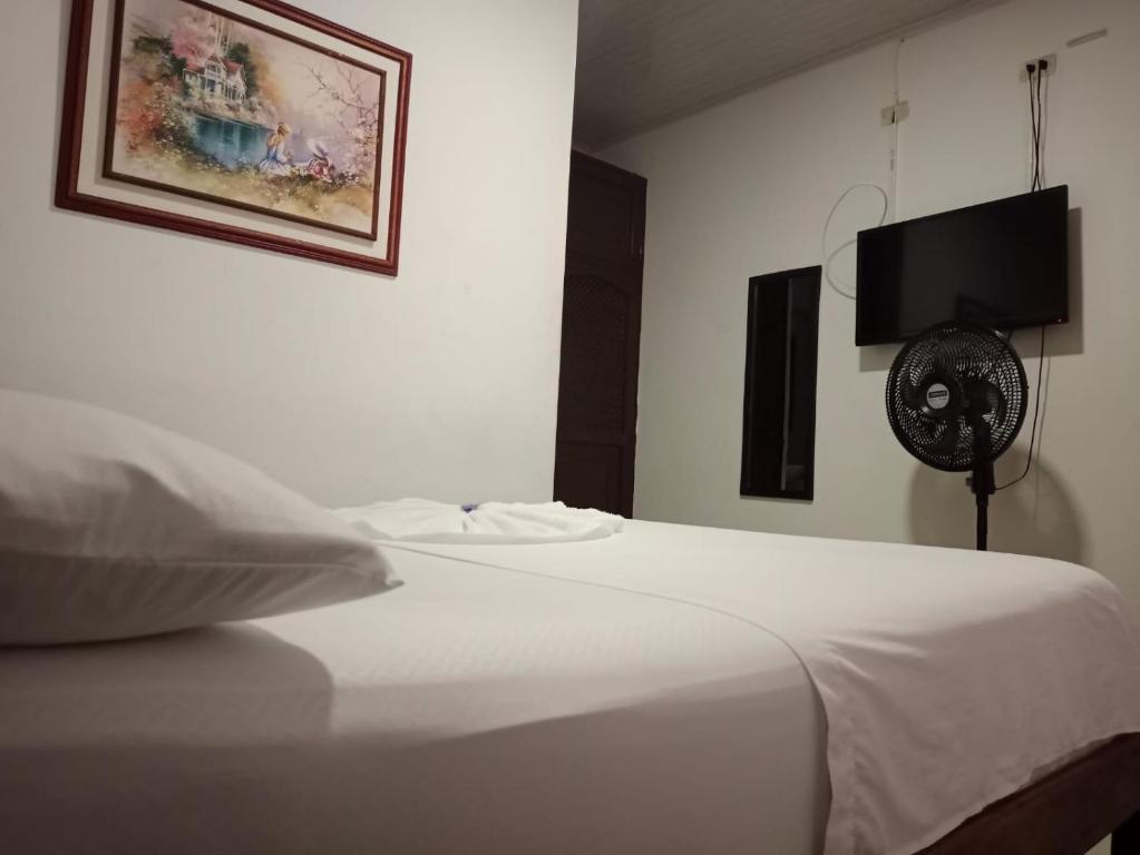 a bedroom with a white bed and a fan at Hotel Unión in Villavicencio
