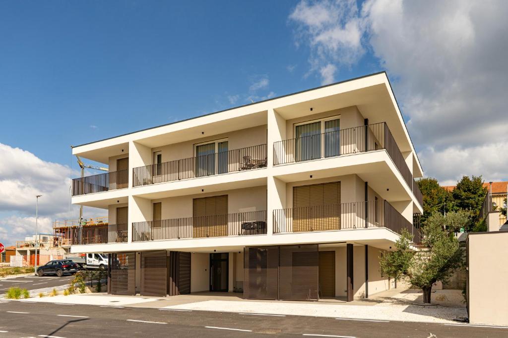 Urban Lodge- Appartamenti in Franciacorta في إيربوسكو: مبنى ابيض فيه بلكونات وموقف سيارات