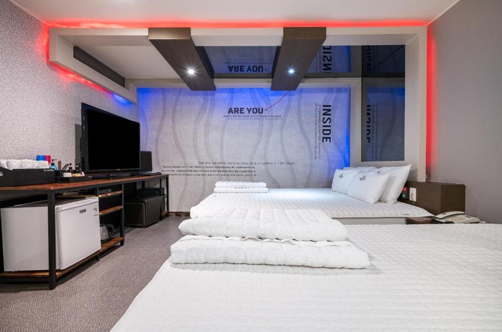 a room with two beds with a tv and avertisement at v motel in Busan