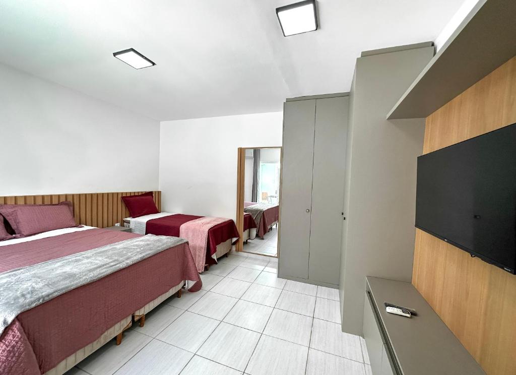 ein Hotelzimmer mit zwei Betten und einem Flachbildfernseher in der Unterkunft Casa de Praia - Brisa do Mar in Aracaju