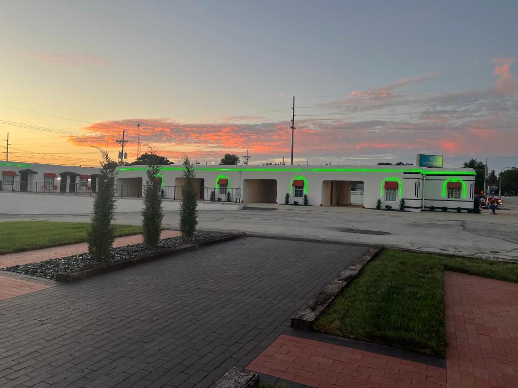 a green building with trees in a parking lot at Boots Court Motel in Carthage