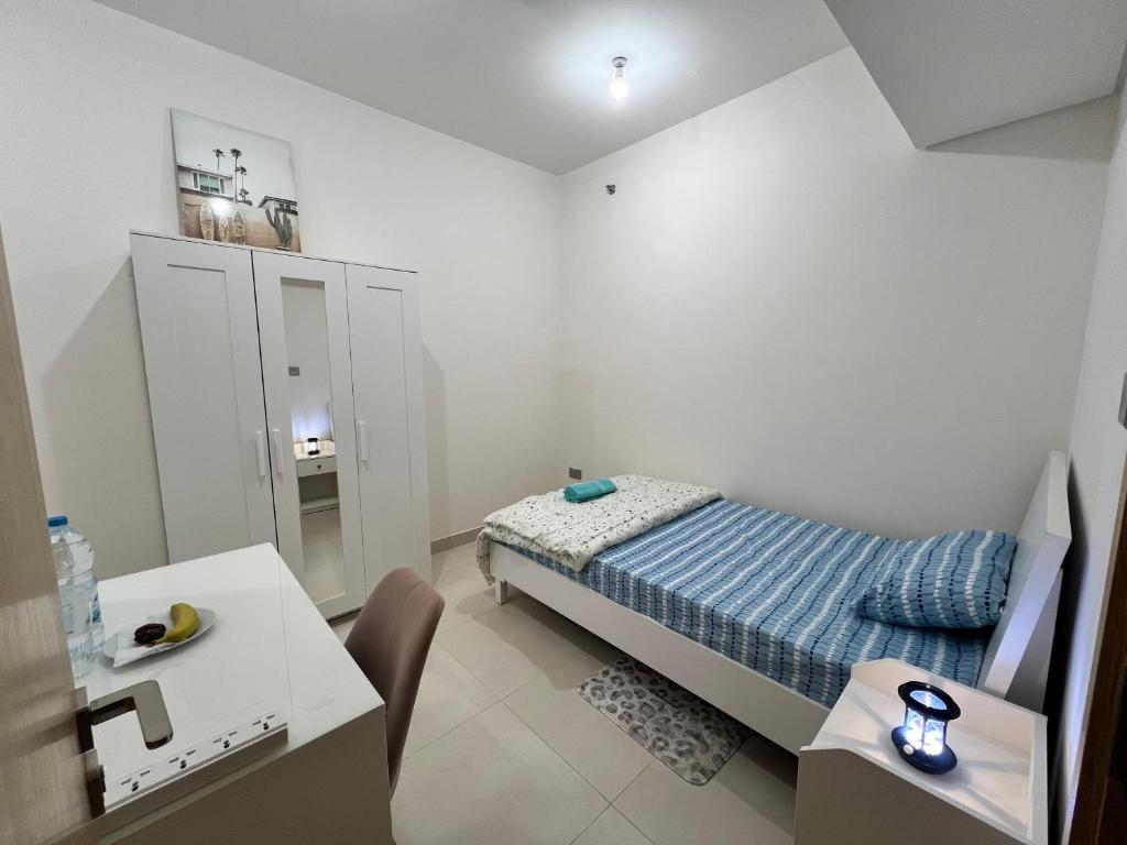 a small white room with a bed and a table at Cozy Room In Abu Dhabi Reem island Near to Galeria Mall in Abu Dhabi