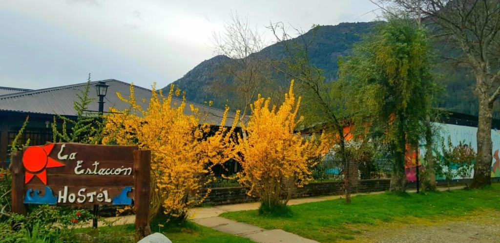 a sign with yellow trees in front of a building at La Estacion Hostel in Lago Puelo