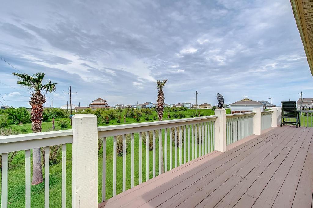 eine Holzterrasse mit einem weißen Zaun und Palmen in der Unterkunft Blessings by the Sea in Port Bolivar