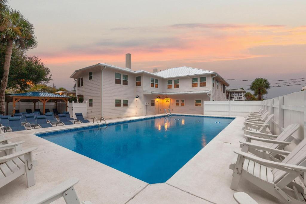 a swimming pool with chairs and a house at Beachside Villa Collection - 6 Bedroom in Tybee Island