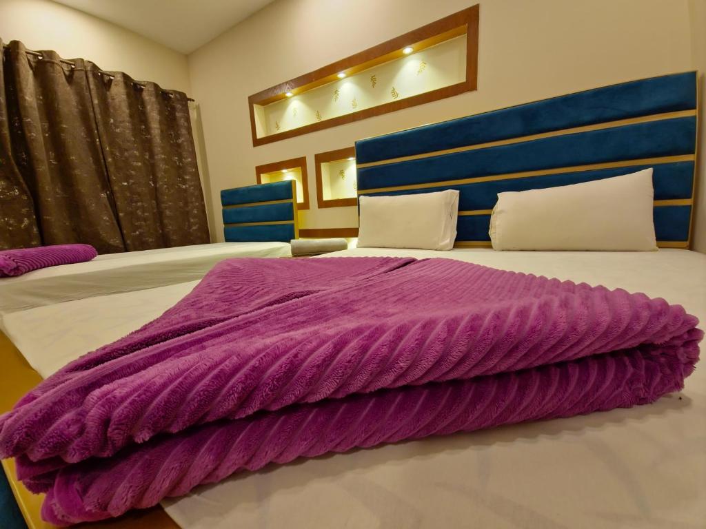 a purple blanket laying on top of a bed at The Oak Residence in Islamabad