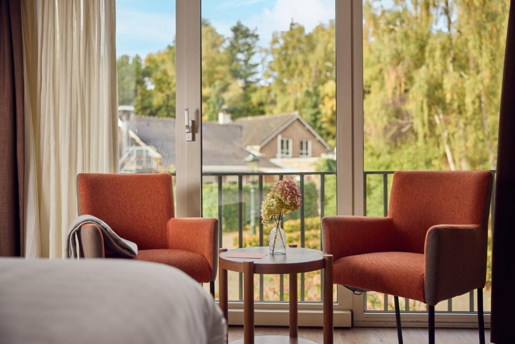 a hotel room with a bed and two chairs and a window at Hotel Duinrand Drunen in Drunen